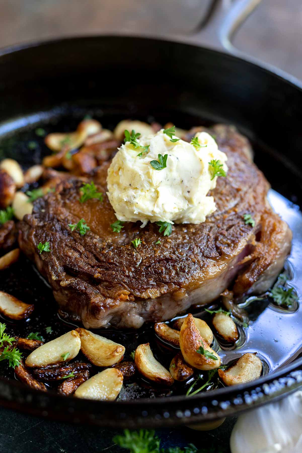 seared ribeye steak in cast iron pan with garlic cloves