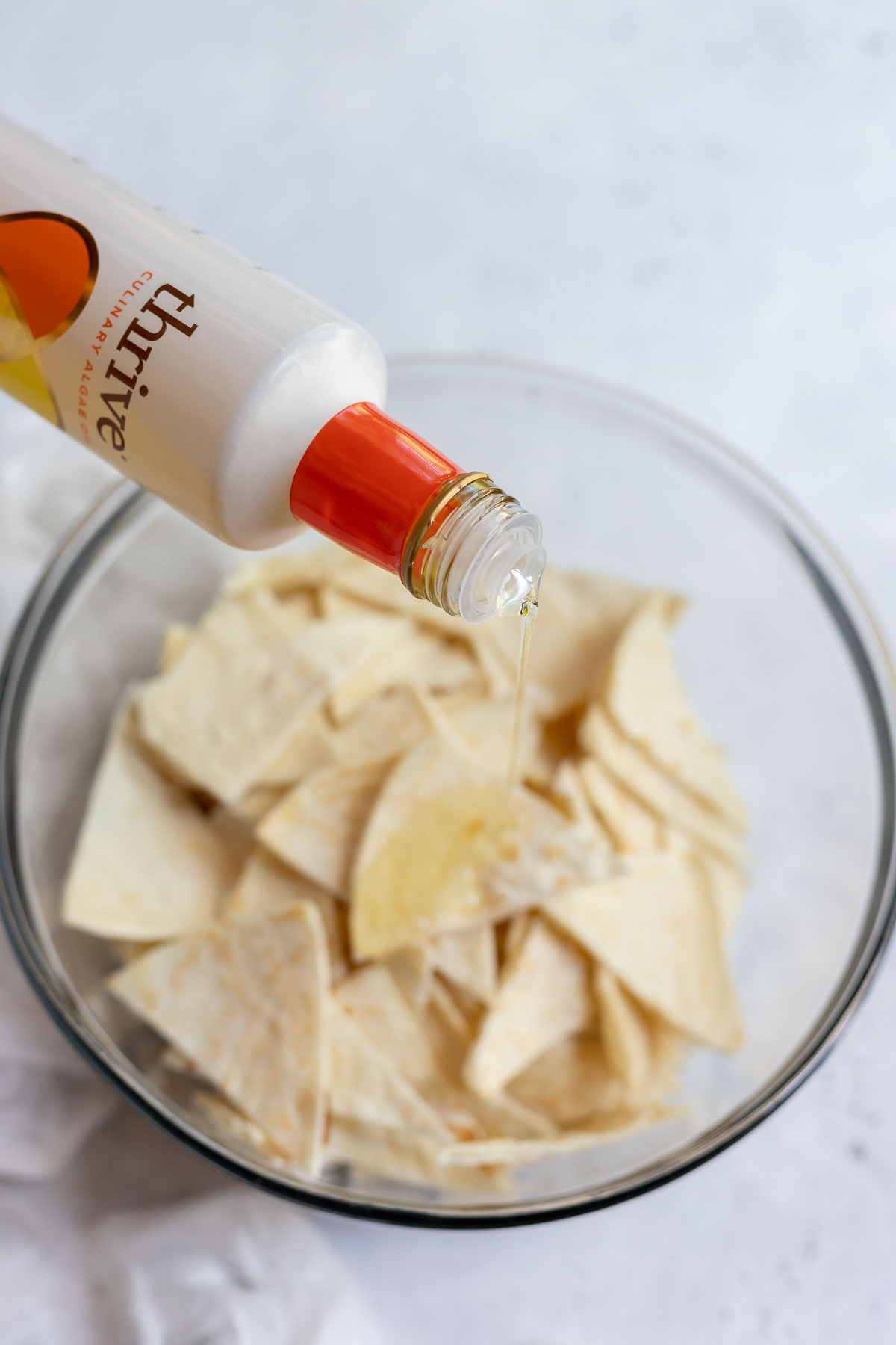 tortilla triangles being drizzled with oil