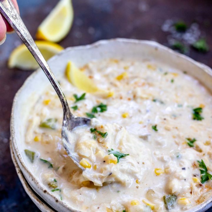 crab corn chowder on white bowl being scooped with a spoon