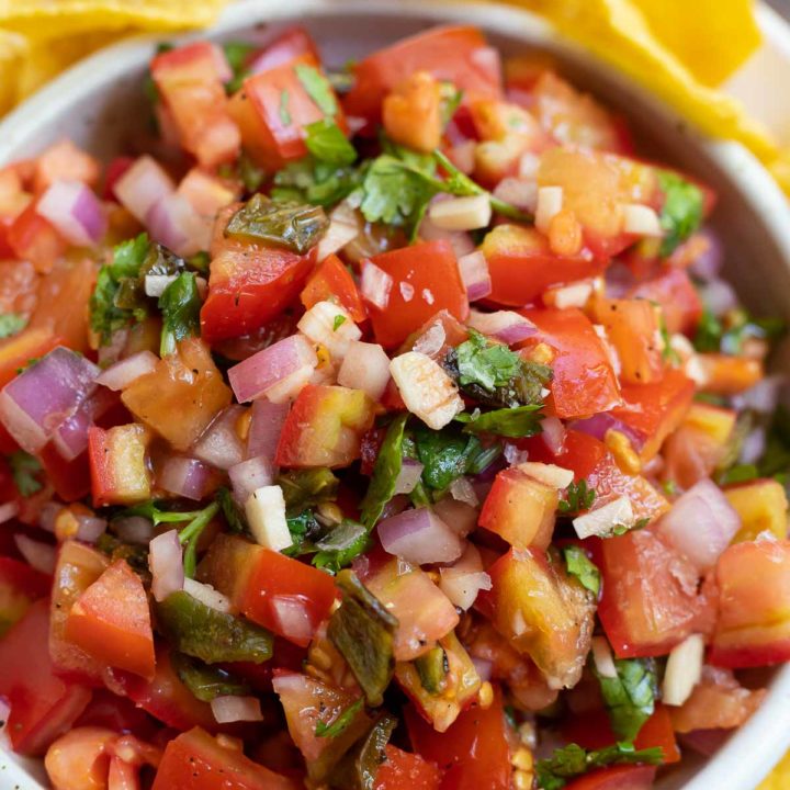 fresh homemade salsa in white bowl surrounded by tortilla chips