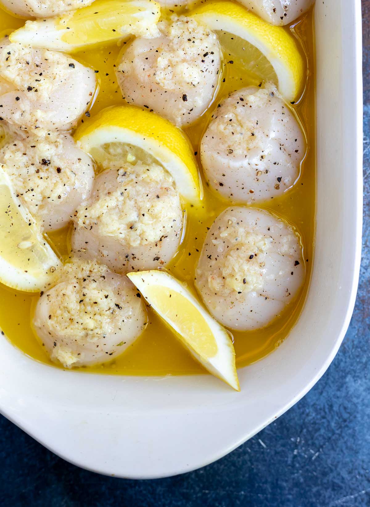 raw scallops in melted butter with lemons