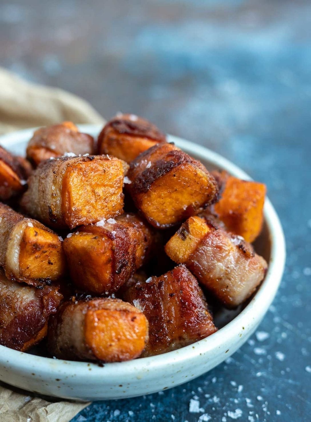 roasted sweet potatoes wrapped in bacon in white dish