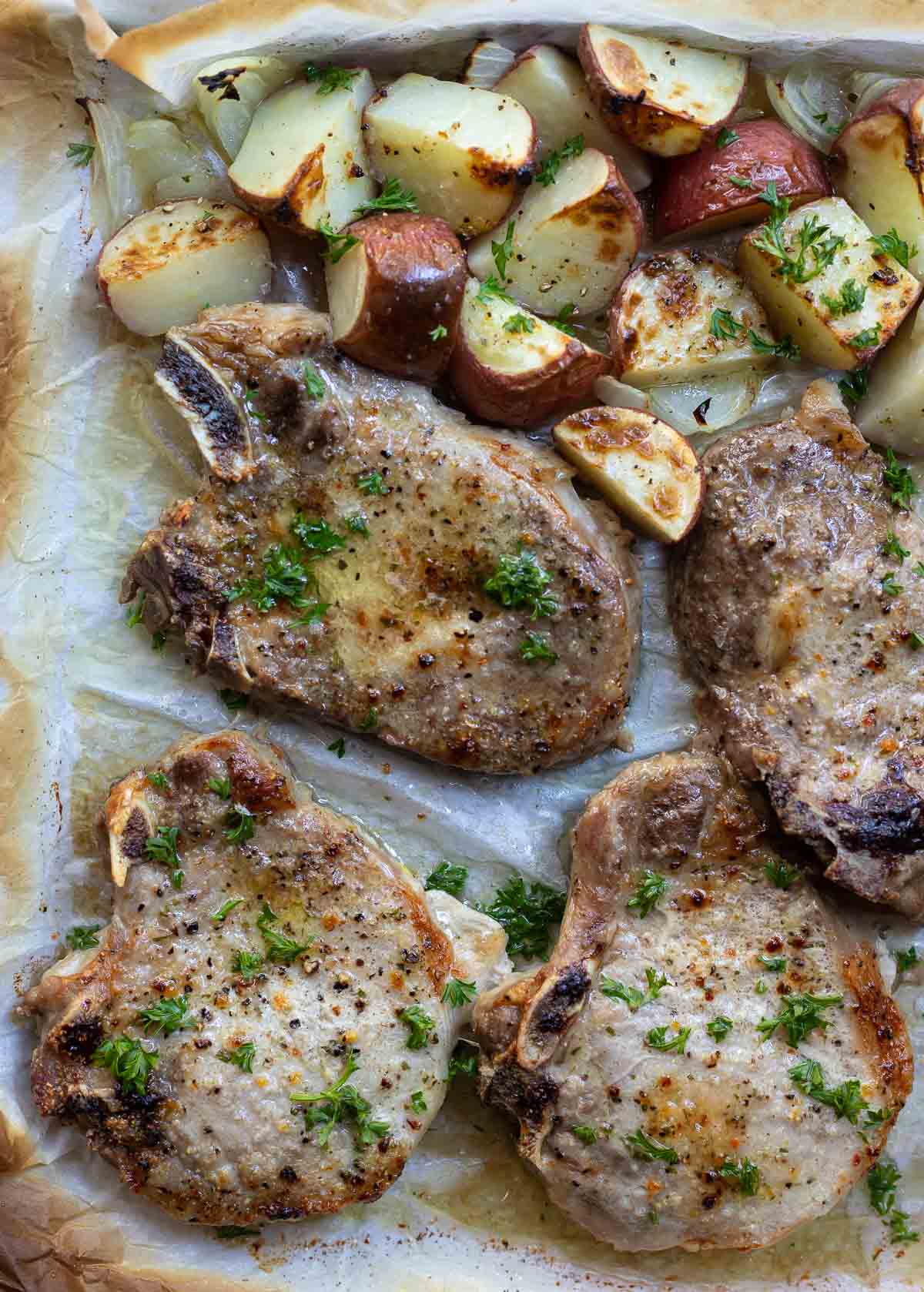 baked pork chops and potatoes on sheet pan