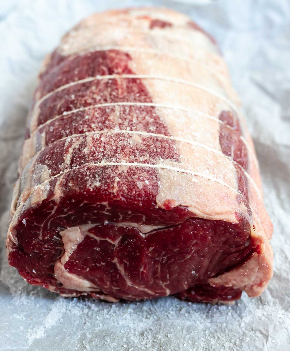 raw prime rib roast wrapped with twine and coated in salt