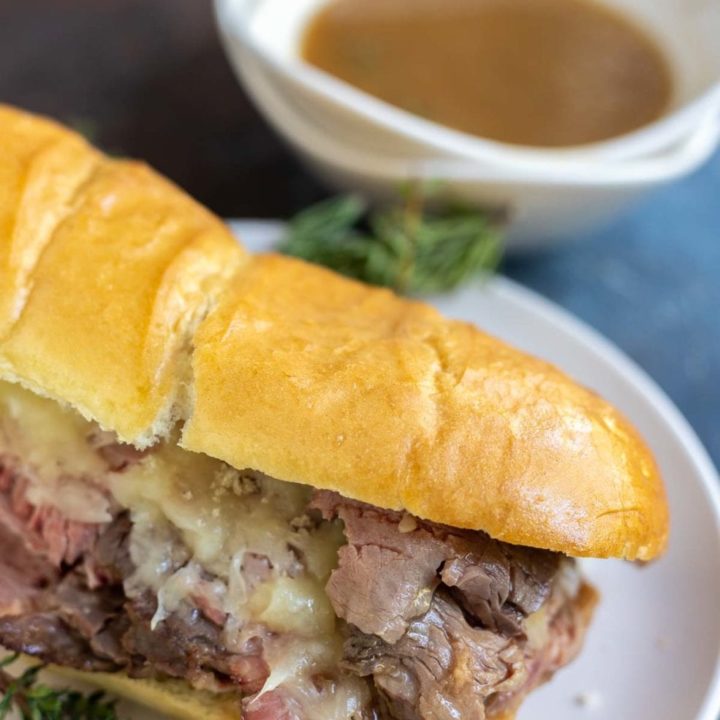 prime rib dip on white plate with bowl of au jus on the side