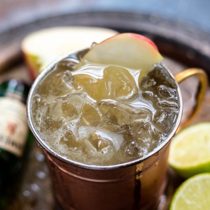 copper cup filled with drink, ice and apple slice