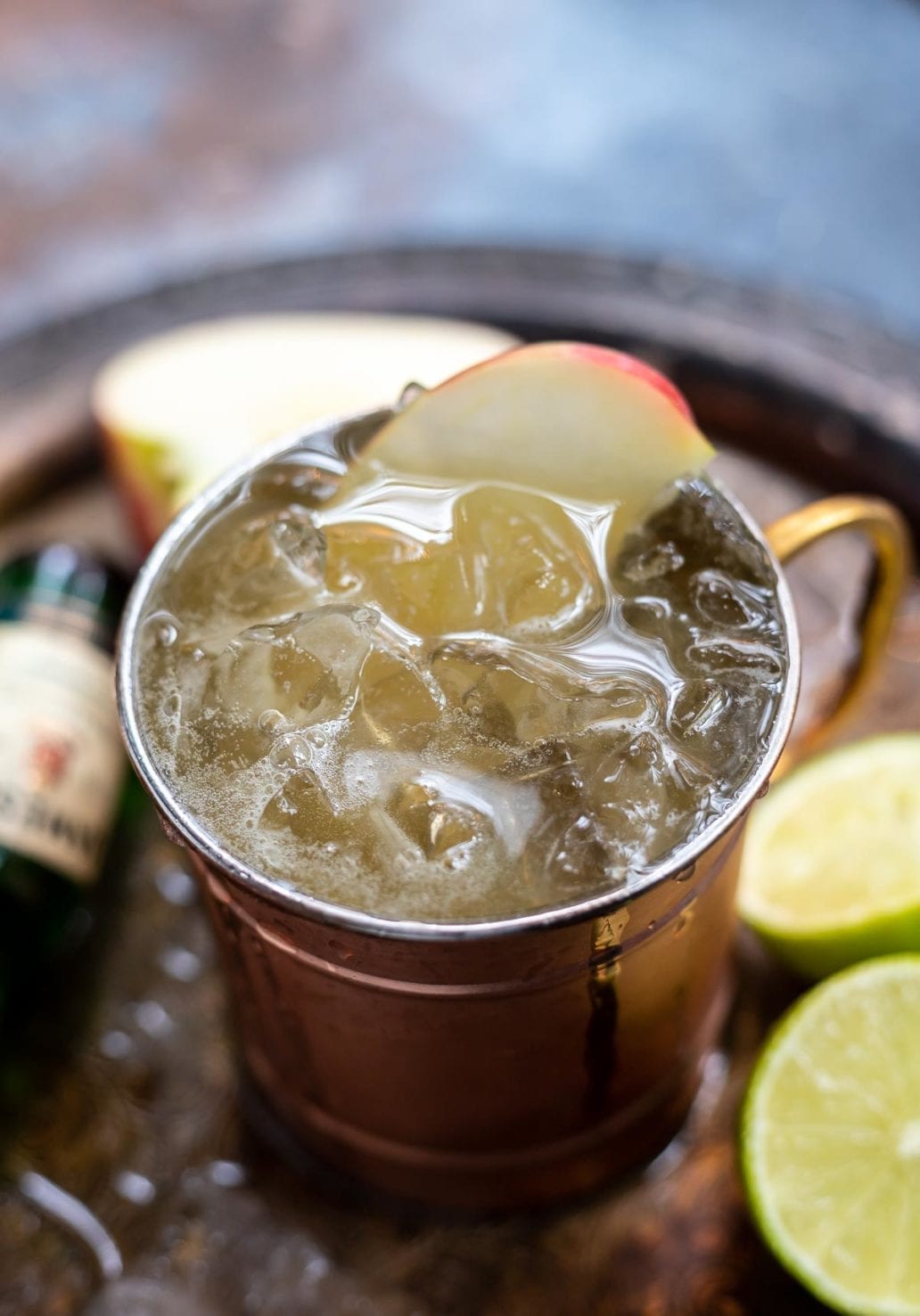 copper cup filled with drink, ice and apple slice