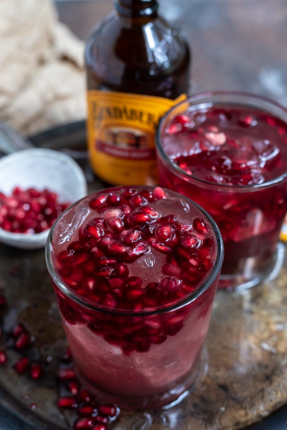 clear glasses with beverage topped with pomegranate seeds