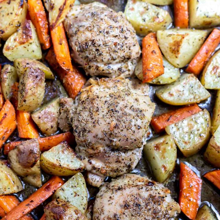 baked chicken thighs, carrots and potatoes on rimmed sheet pan
