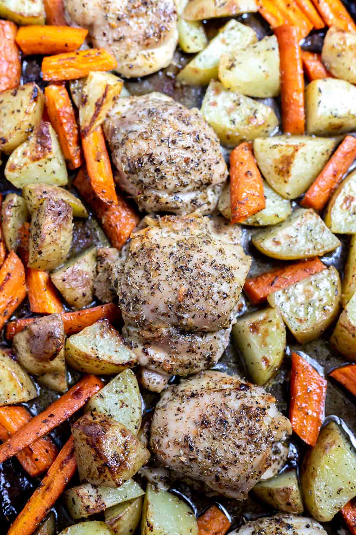 baked chicken thighs, carrots and potatoes on rimmed sheet pan