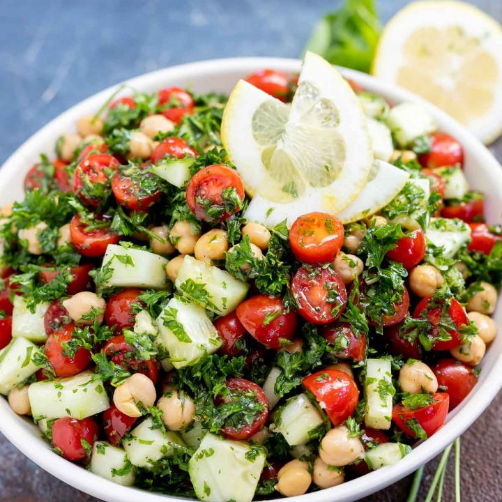 chickpea tabouli salad topped with lemon slices served in white bowl