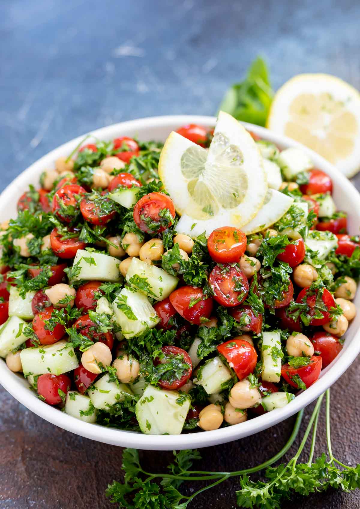 chickpea tabouli salad topped with lemon slices served in white bowl