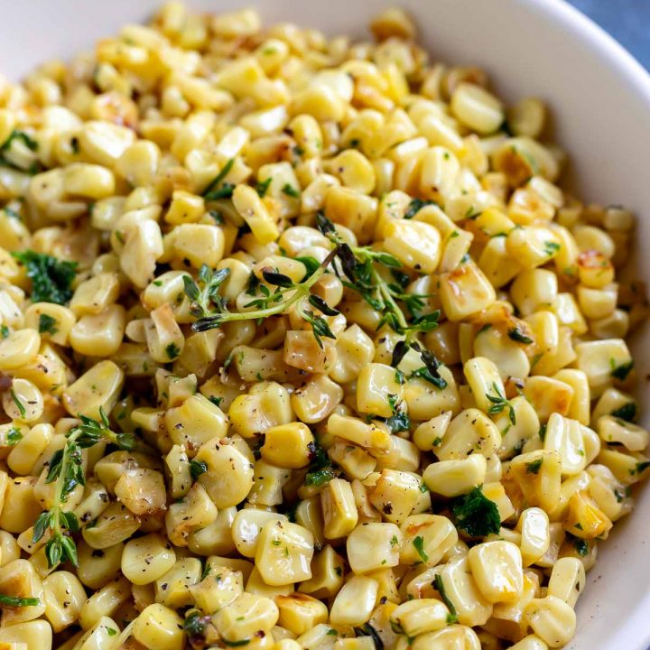 yellow corn with green thyme served in white bowl