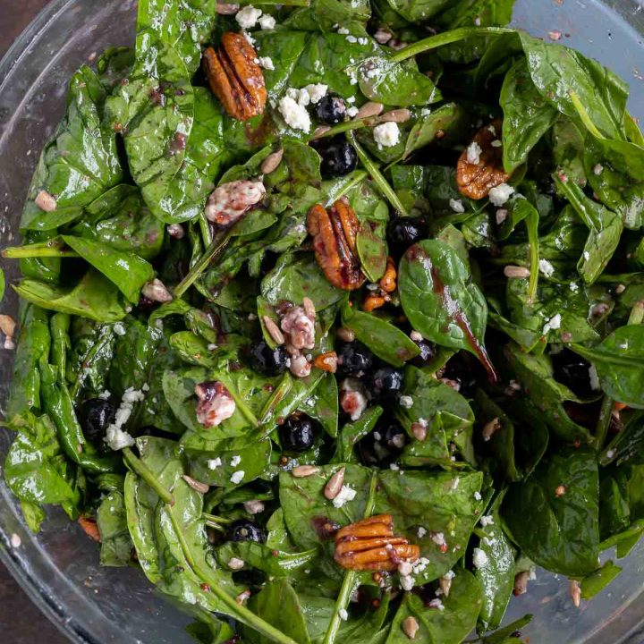 prepared spinach salad in clear glass bowl