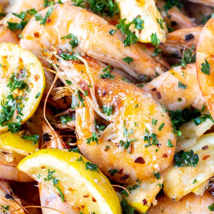 cooked whole pink shrimp with lemon wedges and chopped parsley