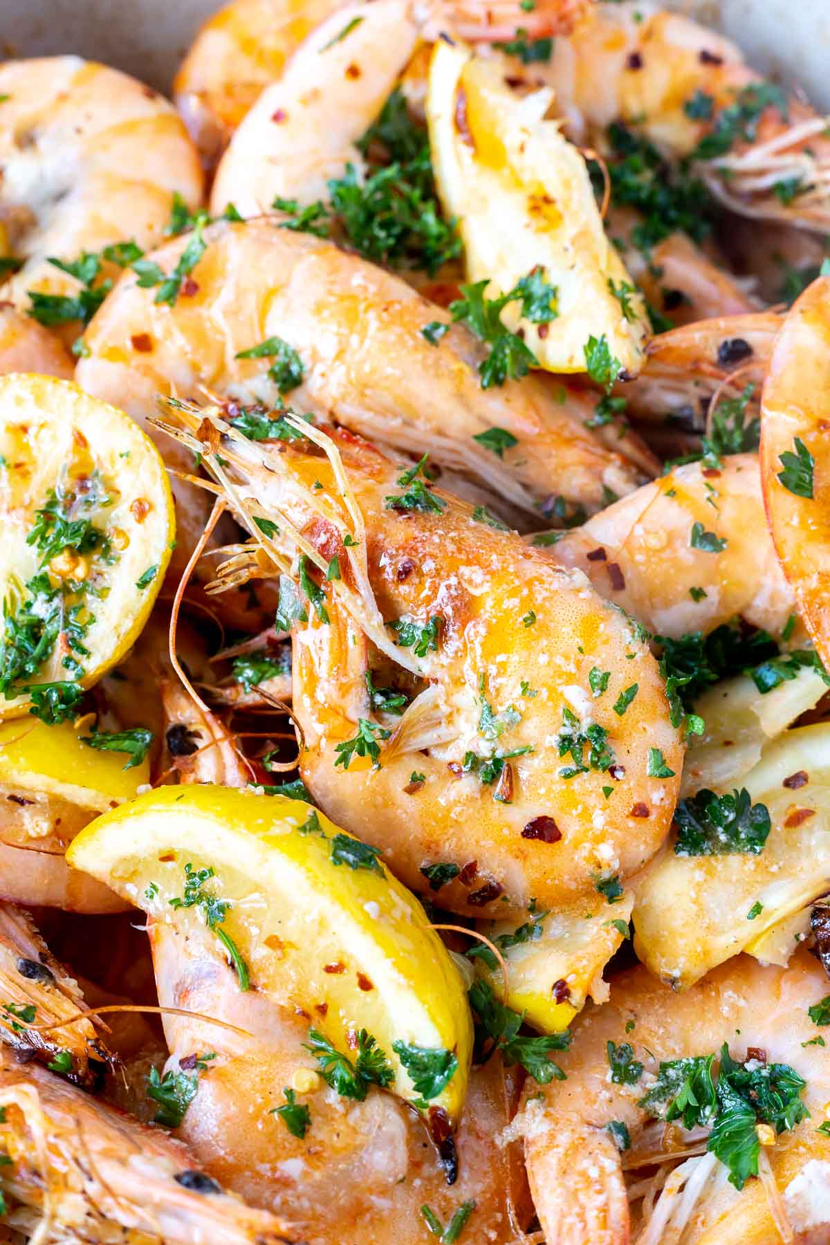 cooked whole pink shrimp with lemon wedges and chopped parsley