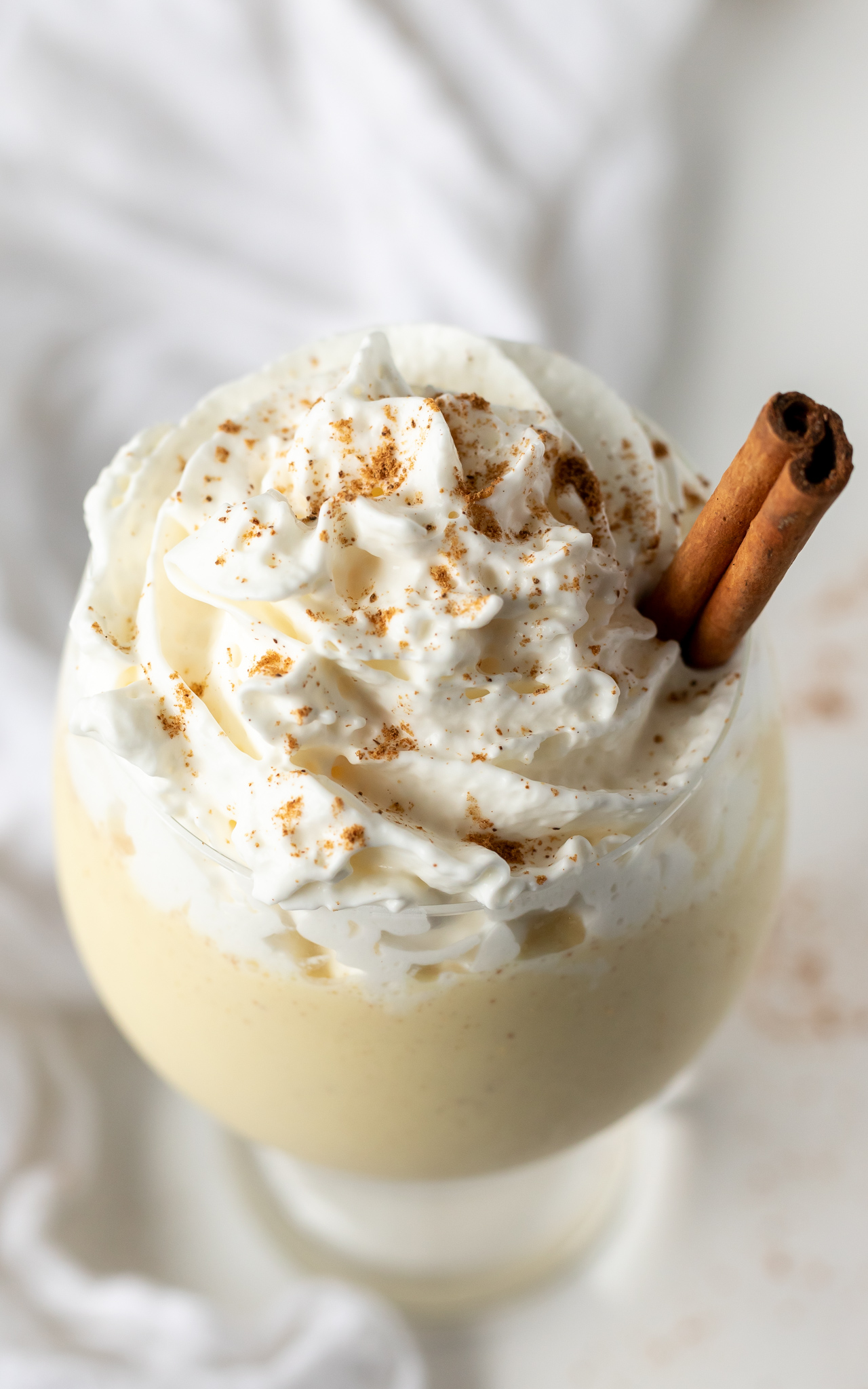 eggnog in glass topped with whipped cream and spices