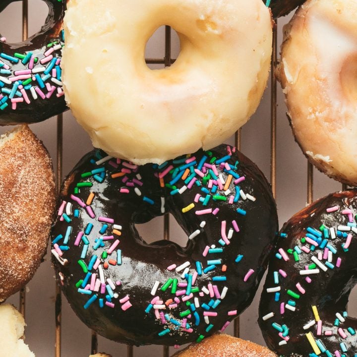vanilla, chcocoalate glazed and cinnamon sugar donuts on rack