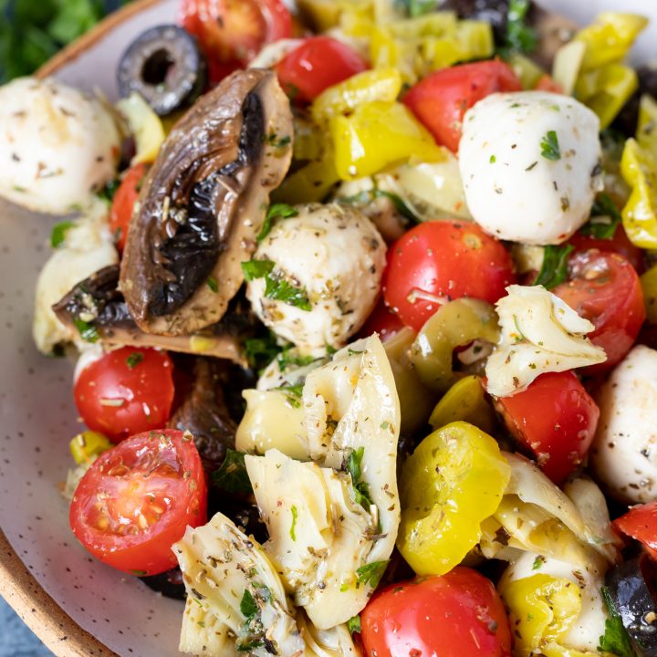 tomatoes, artichokes, mushrooms and mozzarella balls in white bowl