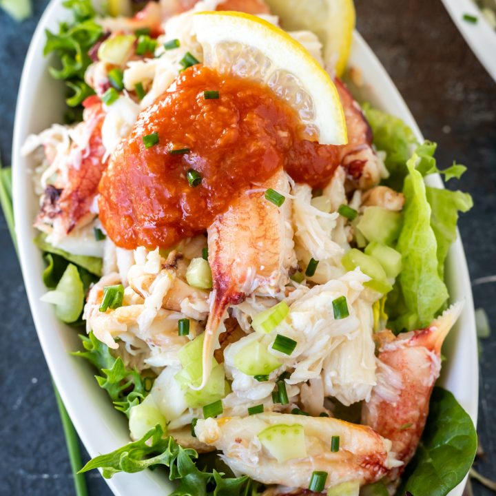 crab meat topped with cocktail sauce in white dish