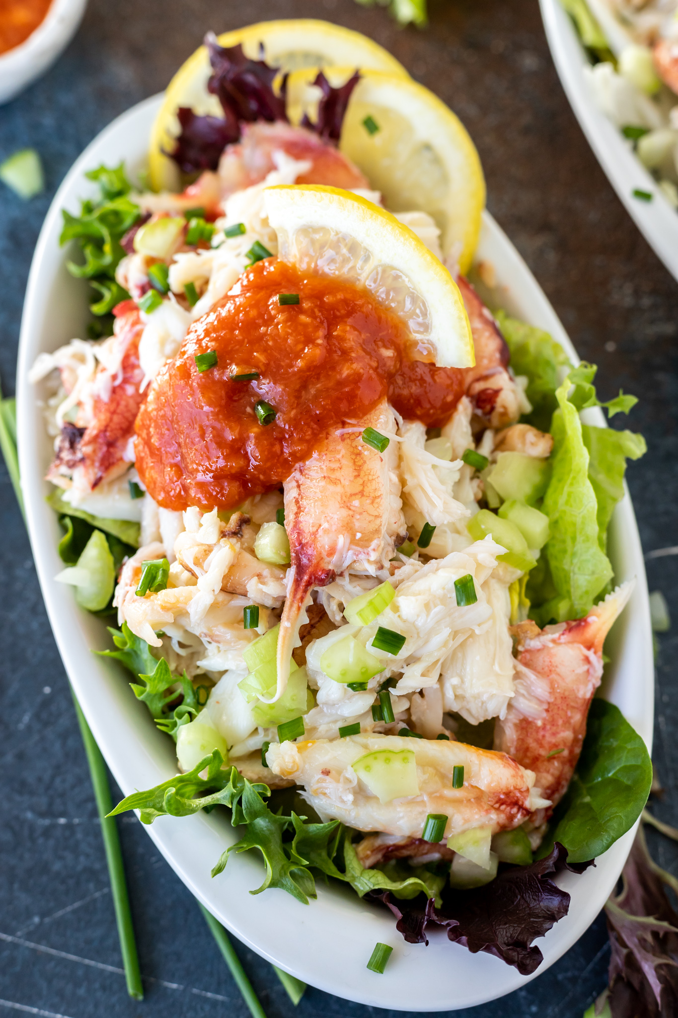 crab meat topped with cocktail sauce in white dish