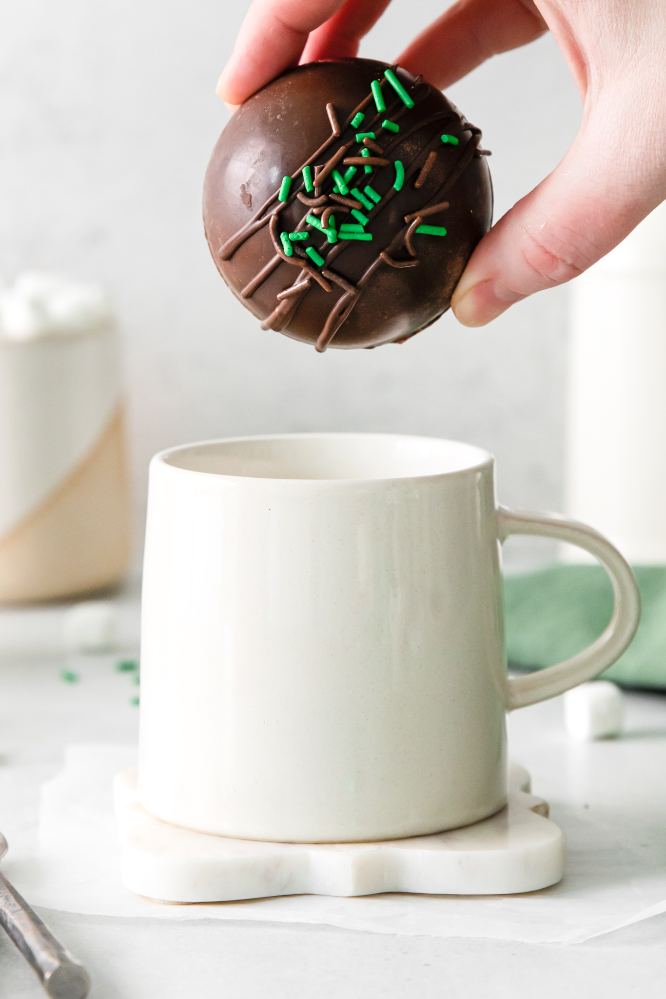 hand holding cocoa bomb over mug