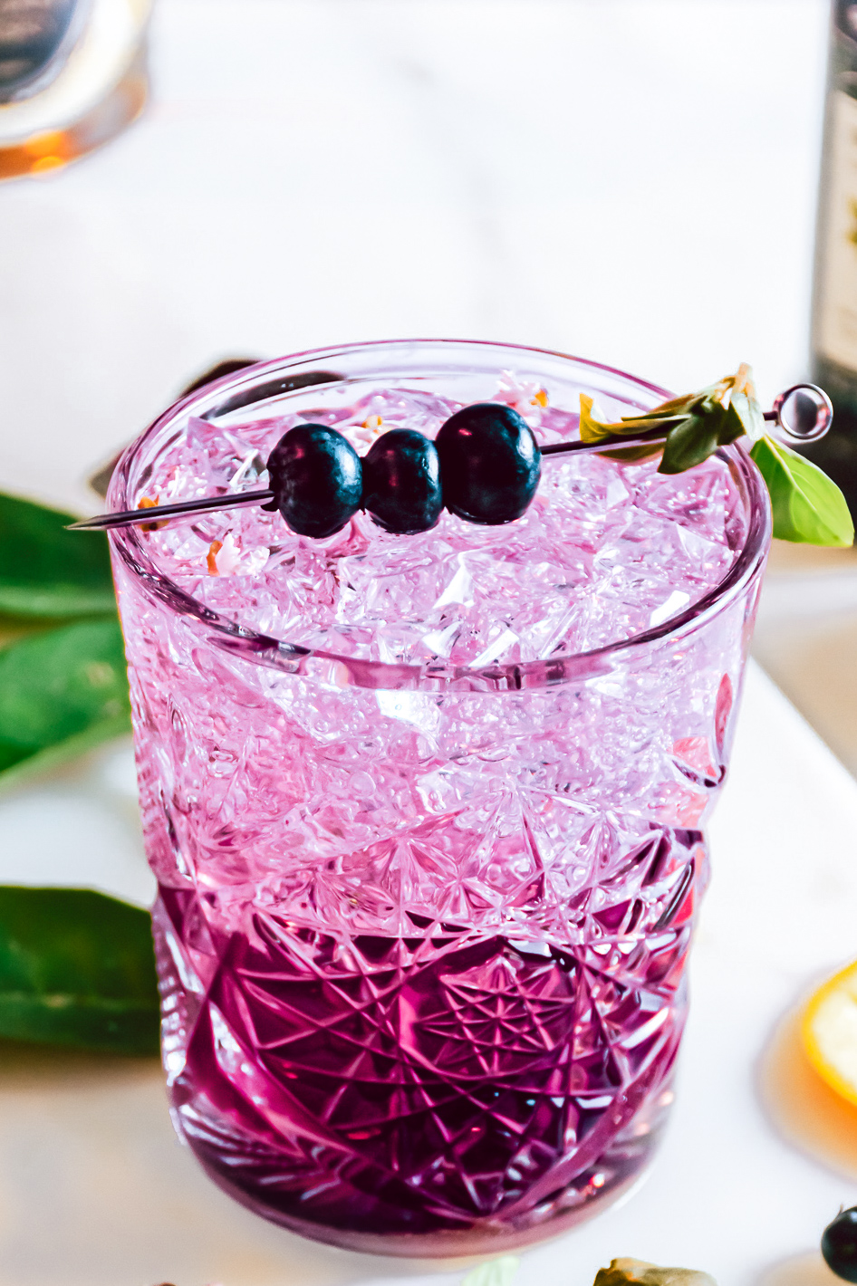 drink in clear glass garnished with blueberries