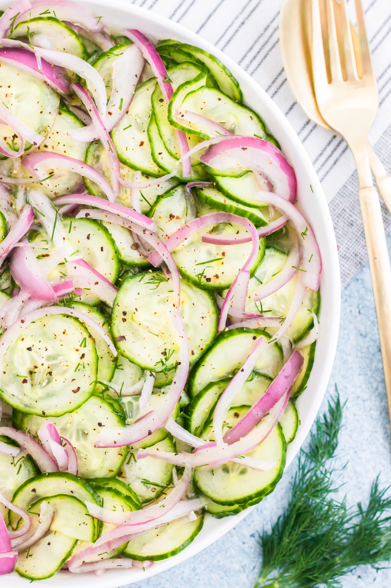 sliced cucumbers and onions in white bowl