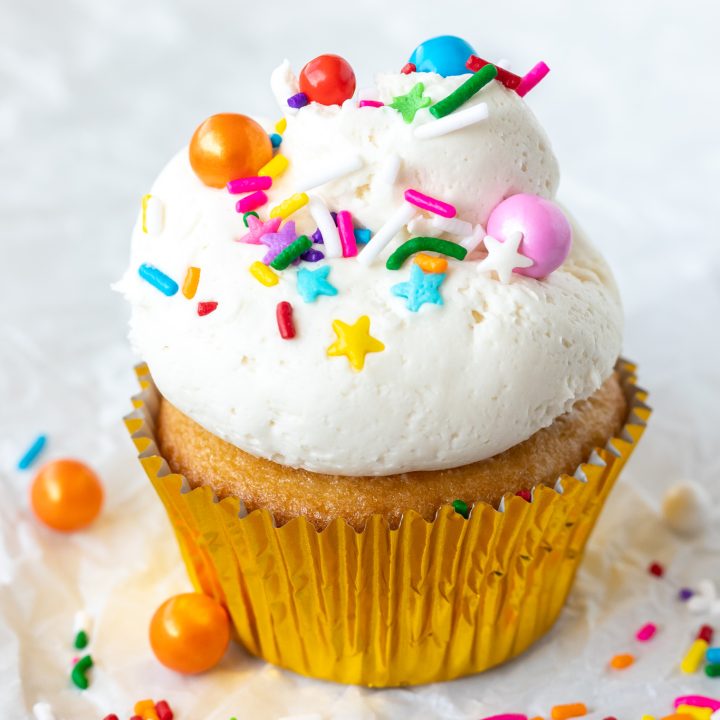 cupcake topped with white frosting and colorful sprinkles