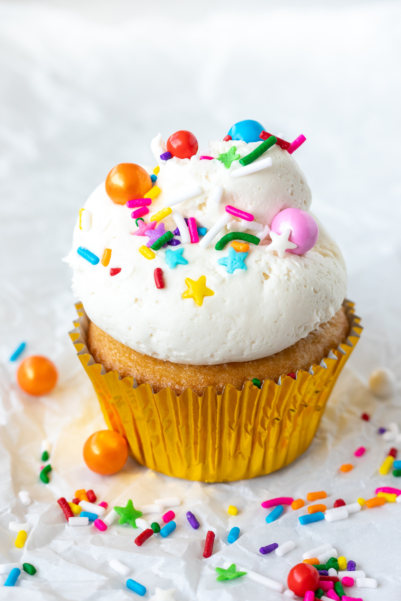 cupcake topped with white frosting and colorful sprinkles