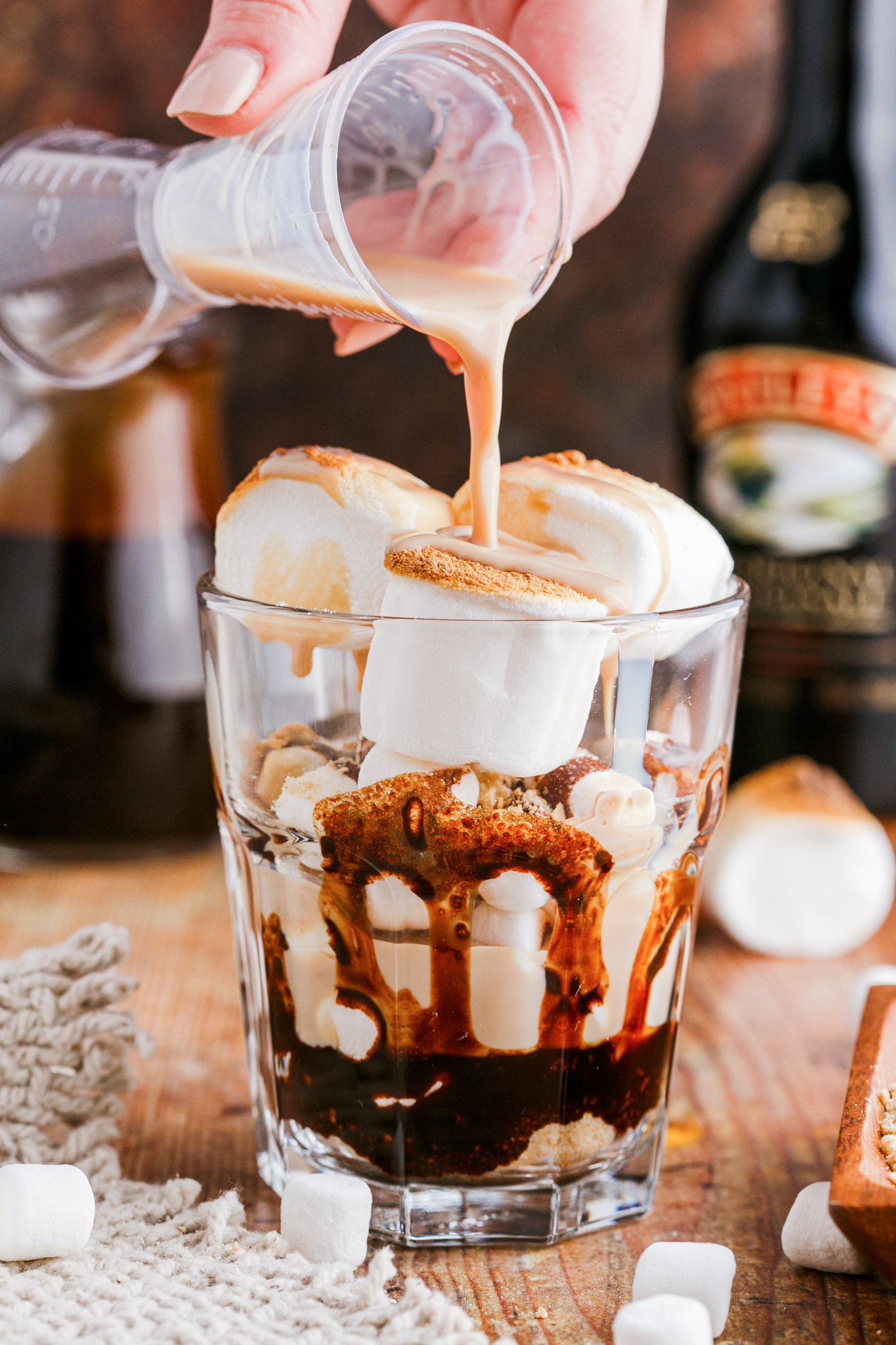 hand pouring baileys over marshmallows