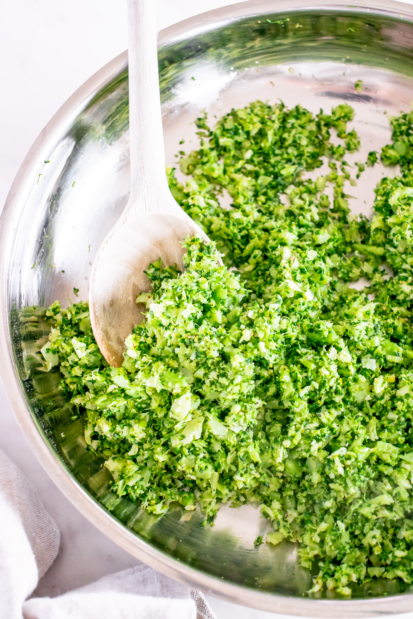 riced broccoli in pan with wooden spoon