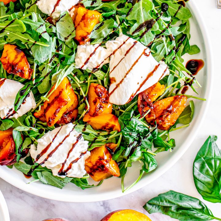 burrata, peaches and arugula on white plate