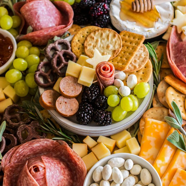 meats cheeses and fruits arranged on a wooden board