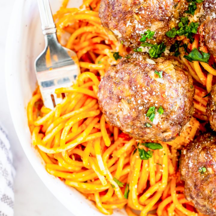 meatballs on top of pasta in white bowl