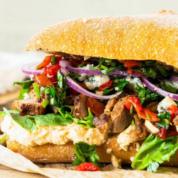 prepared sandwich with steak, greens and hummus