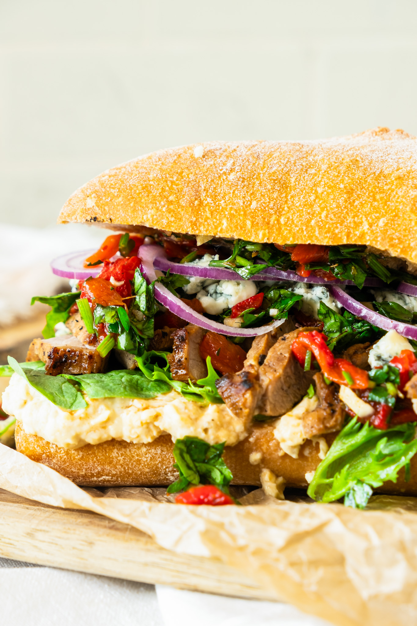 prepared sandwich with steak, greens and hummus