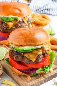 prepared cheeseburger on wooden cutting board