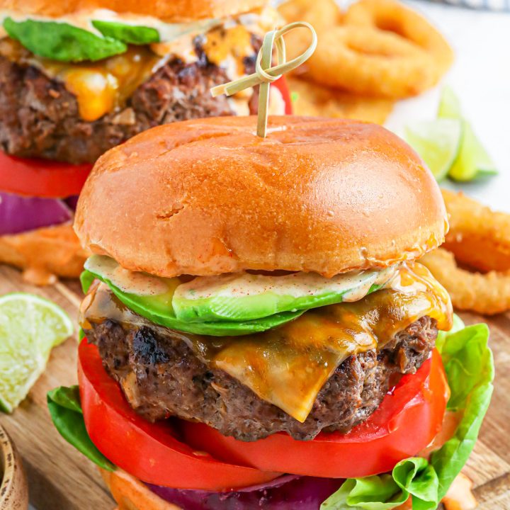 prepared cheeseburger on wooden cutting board